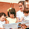 Mamá y sus tres hijos están mirando la ilustración dentro del libro familiar personalizado, que es un gran regalo para tres niños o un gran regalo para el Día de la Madre.